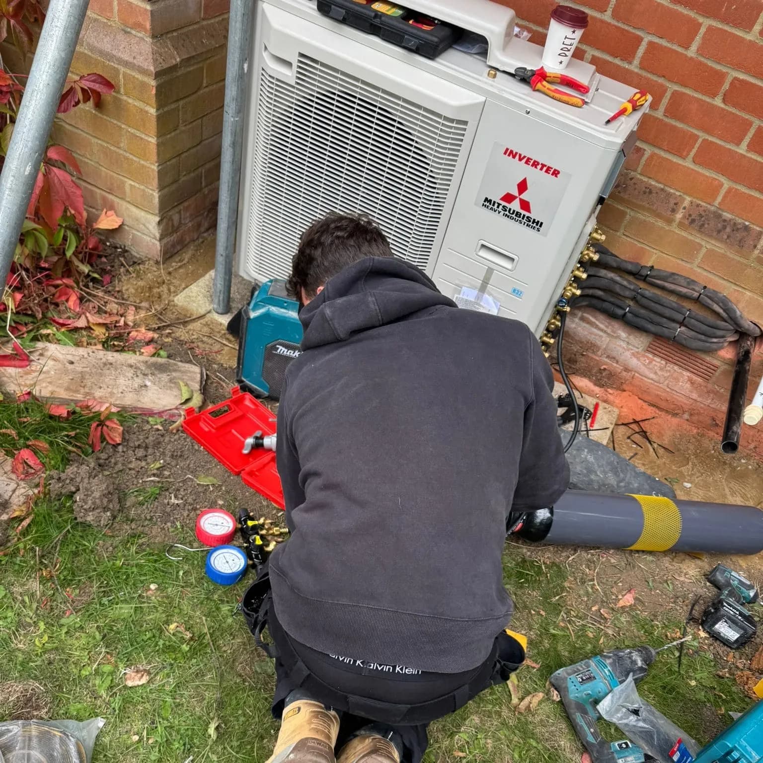 Engineer connecting refrigerant gauges to a Mitsubishi Electric outdoor unit